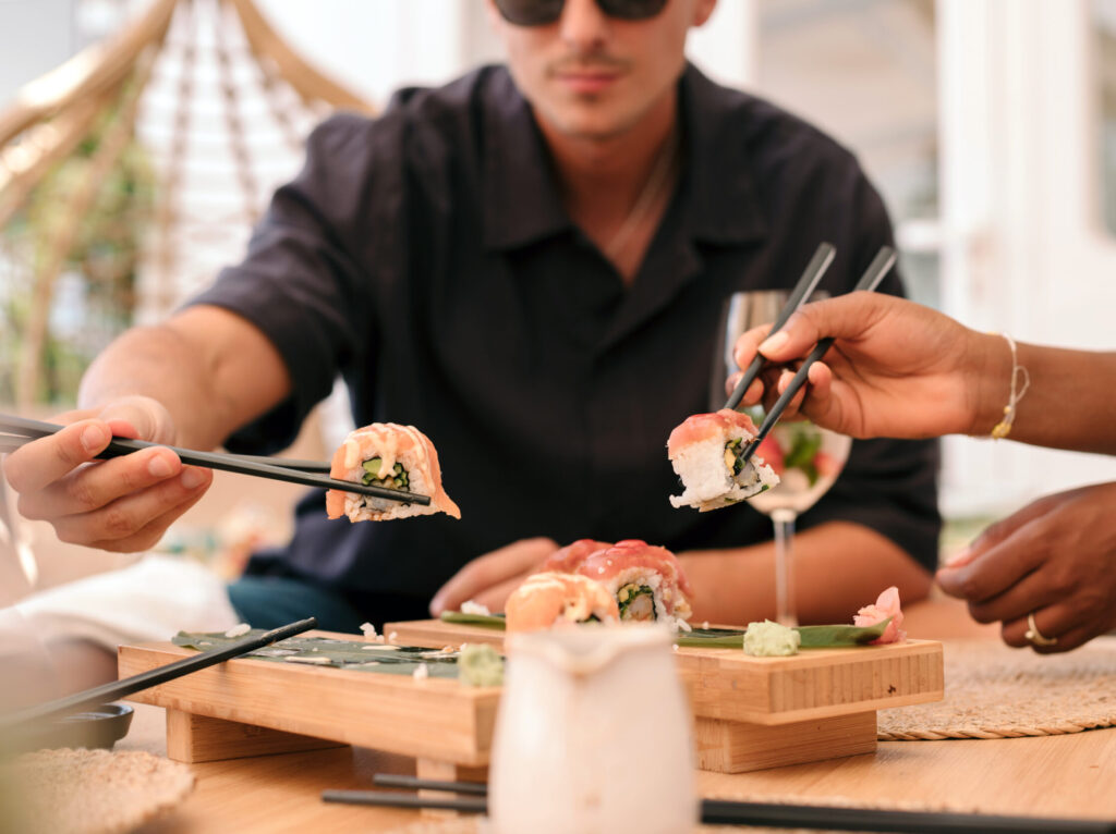 Young people eating sushi in a restaurant. Close up of the sushi pieces.